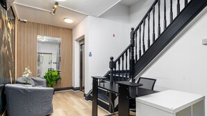 A modern interior with a staircase, a grey sofa, a small table, and a white cabinet. - City Gate Guest House (London)