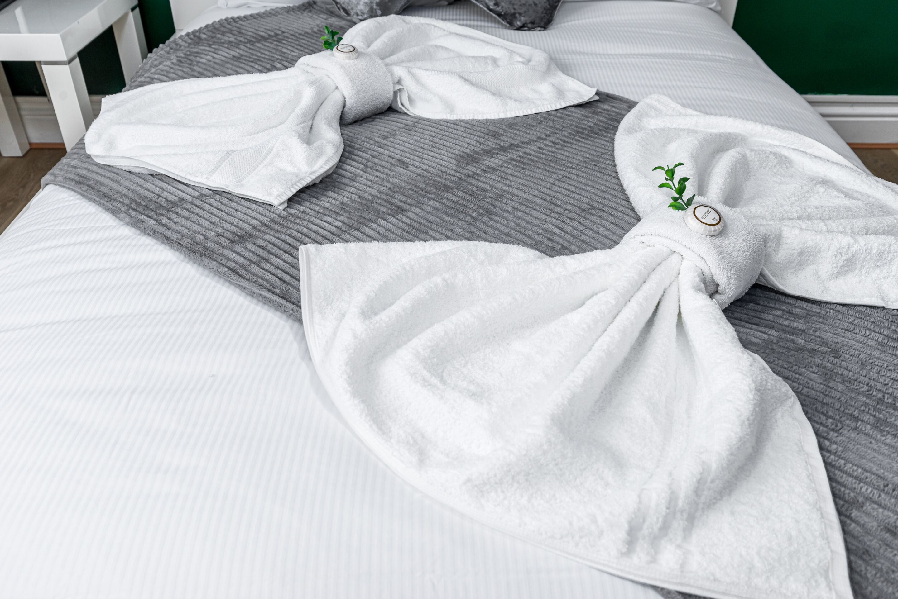 A neatly made bed with white towels and a gray blanket.