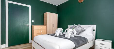 Un dormitorio con una cama, una mesita de noche, un aparador y una puerta.