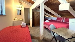 A cozy attic bedroom with a red bed, a small table, and a wooden ceiling. - 118 Standard 2 Bedroom Condo by RedAwning (Mammoth Lakes)