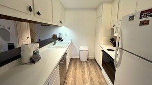 A narrow kitchen with white cabinets, a sink, a stove, and a refrigerator. - 118 Standard 2 Bedroom Condo by RedAwning (Mammoth Lakes)