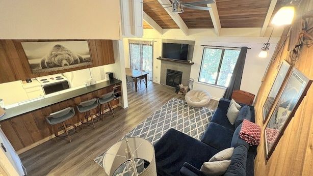 A modern living room with a dark blue sofa, a fireplace, and a kitchen area with a bar counter and stools. - 118 Standard 2 Bedroom Condo by RedAwning (Mammoth Lakes)