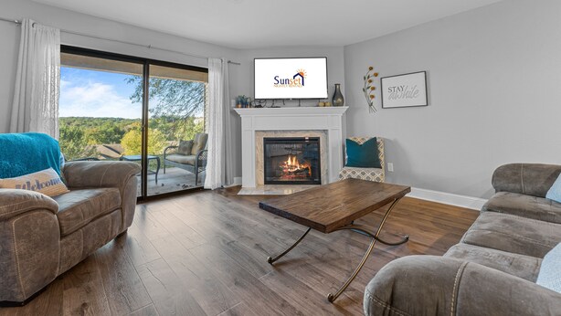 Una sala de estar moderna con chimenea, un televisor montado encima y un amplio ventanal corredero que da a un espacio al aire libre.
