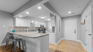 Una cocina moderna con una isla grande, armarios blancos y un salpicadero con diseño.