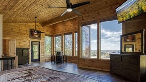 A spacious room with a large bed, wooden ceiling, and multiple windows offering a view of the outdoors. - Smoky Lake Retreat 3 Bedroom Cabin by RedAwning (Dandridge)