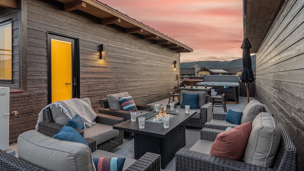 Une terrasse extérieure aménagée avec des meubles en osier, un foyer et une vue sur les montagnes.