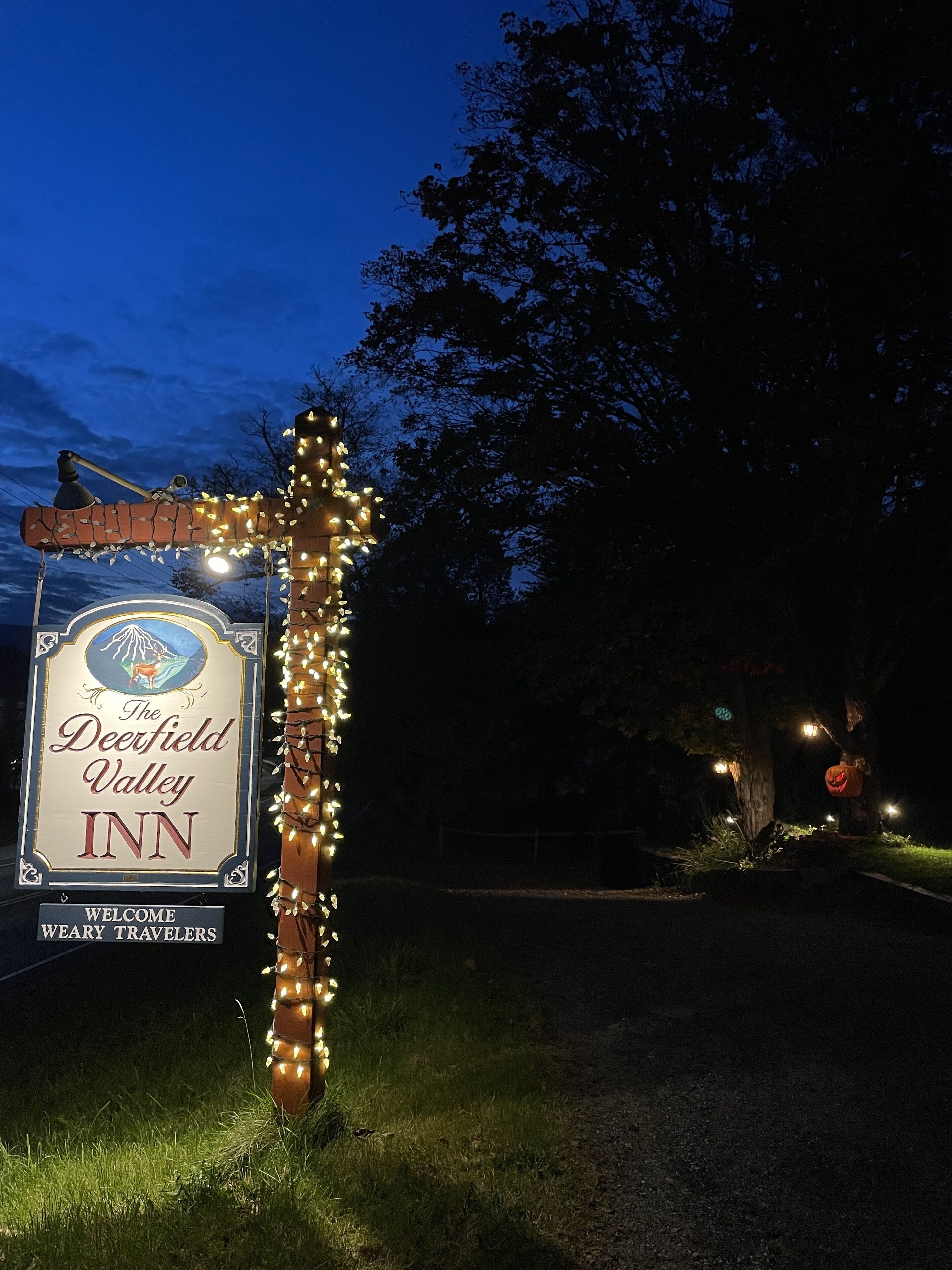 A sign for Deerfield Valley Inn with a rustic design and a welcoming message.