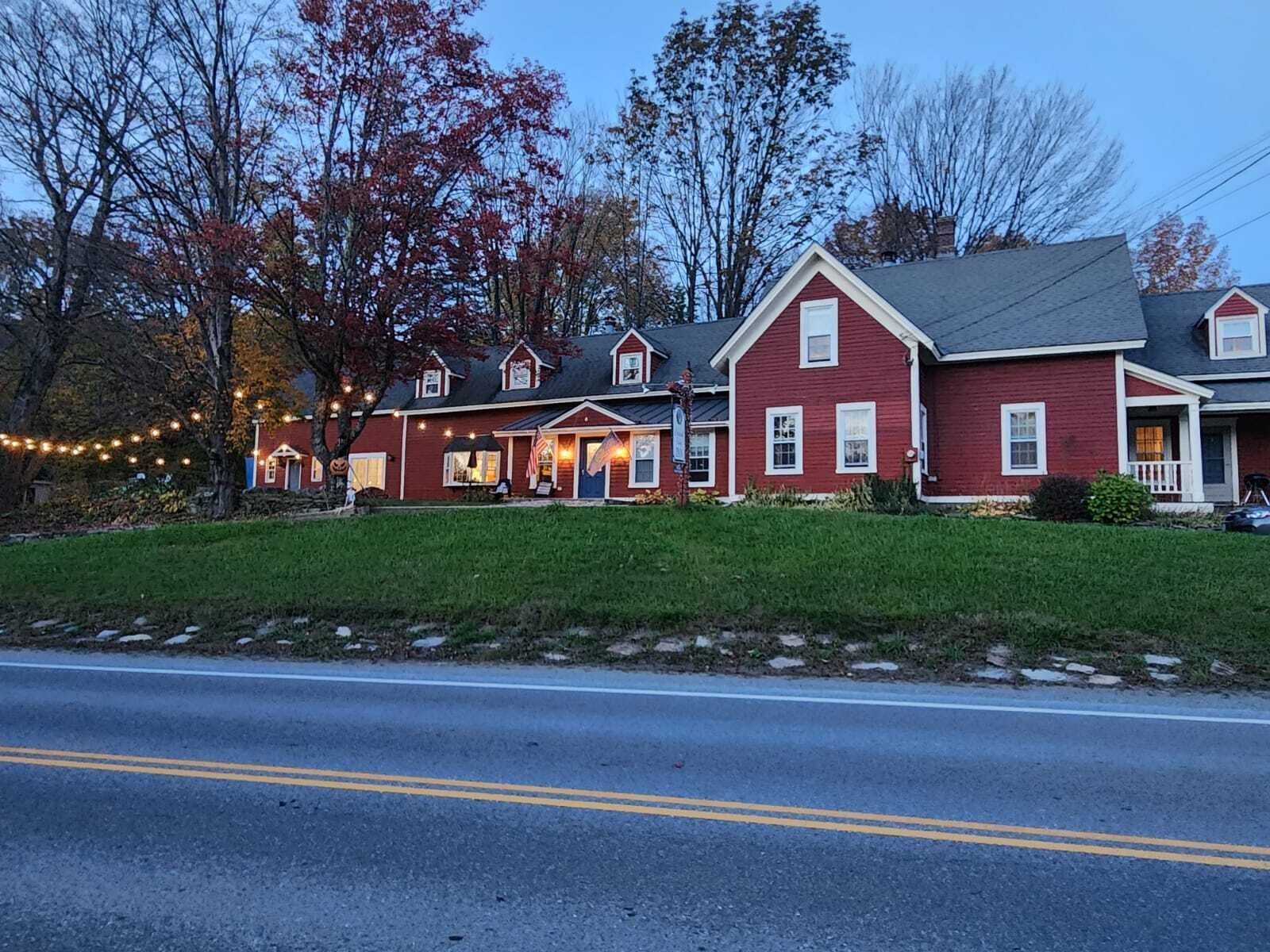 A two-story red house with a front porch, a garage, and a well-maintained lawn.