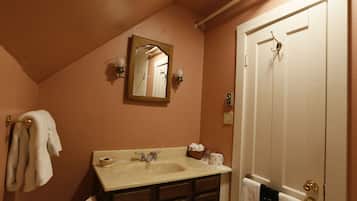 Un baño con lavabo, espejo, toallero y una puerta con una toalla colgada.