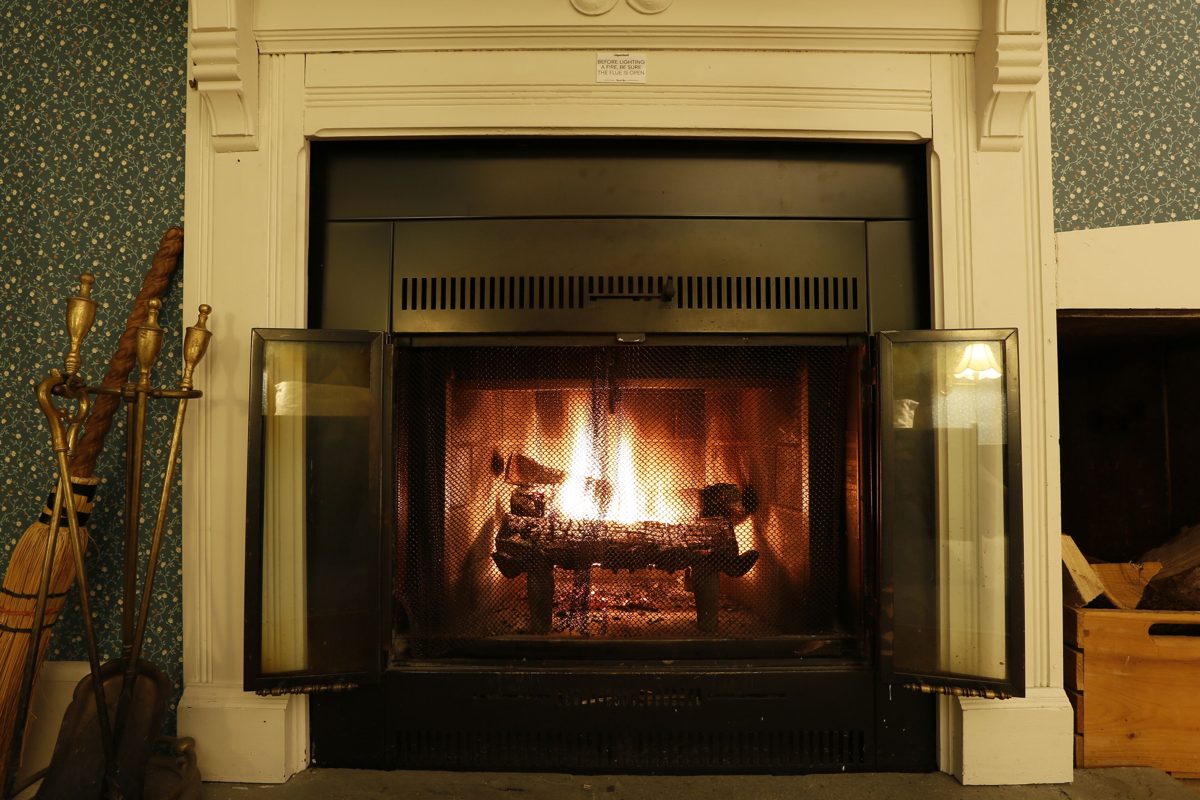 Une cheminée avec un feu, une étagère au-dessus du foyer et une inscription placée au-dessus.