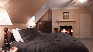 Une chambre à coucher avec une couvre-lit matelassé de couleur sombre, une tête de lit en bois, une cheminée et un ventilateur de plafond.