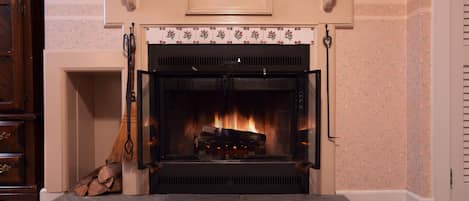 Una chimenea con repisa, fuego encendido en su interior y una pared decorativa con motivos florales.