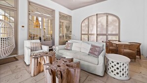 A spacious living room with a white sofa, wooden coffee table, and wicker chairs.