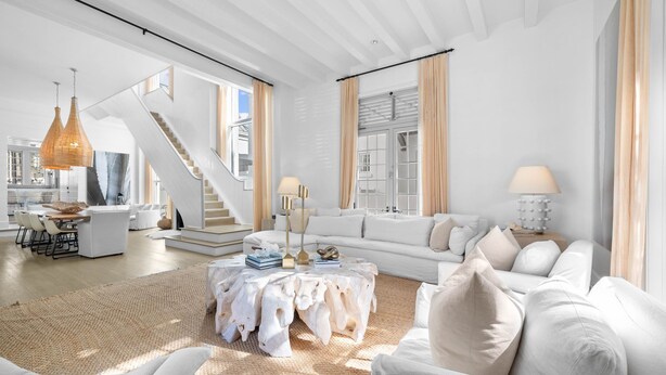 A spacious living room with a white sofa, a coffee table, and a staircase leading to an upper level.