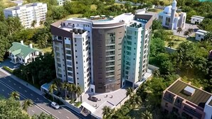 Un hôtel de grande hauteur, avec de nombreux étages, entouré d’une végétation luxuriante et offrant une vue sur l’océan.