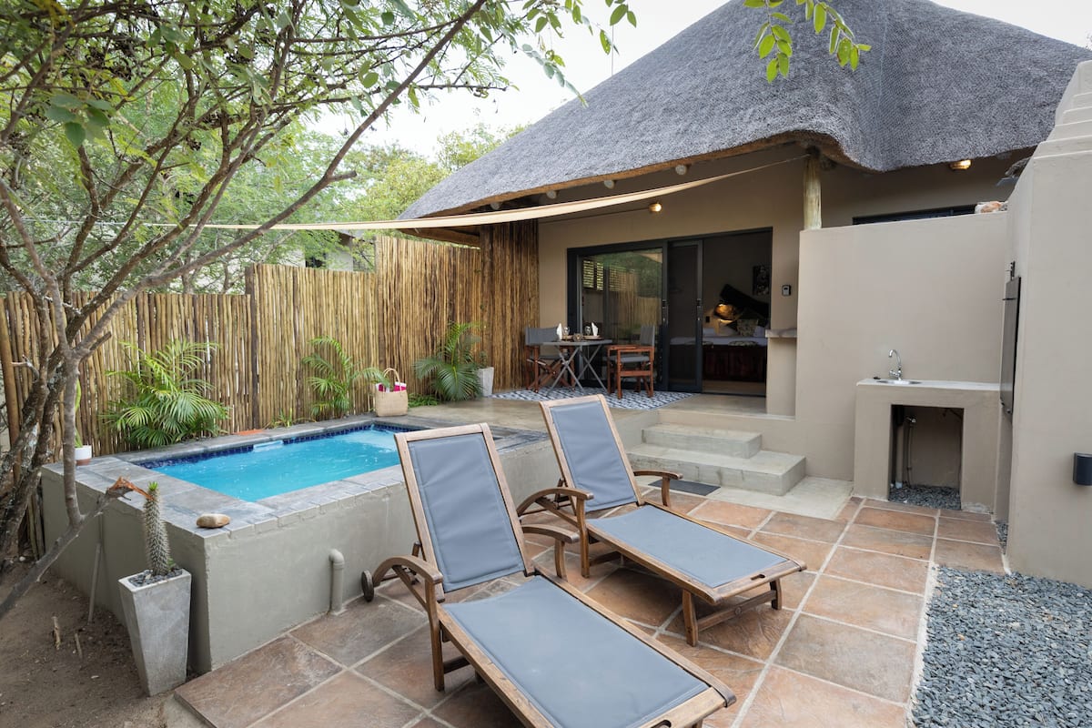 A pool area with lounge chairs, a barbecue, and a covered patio.