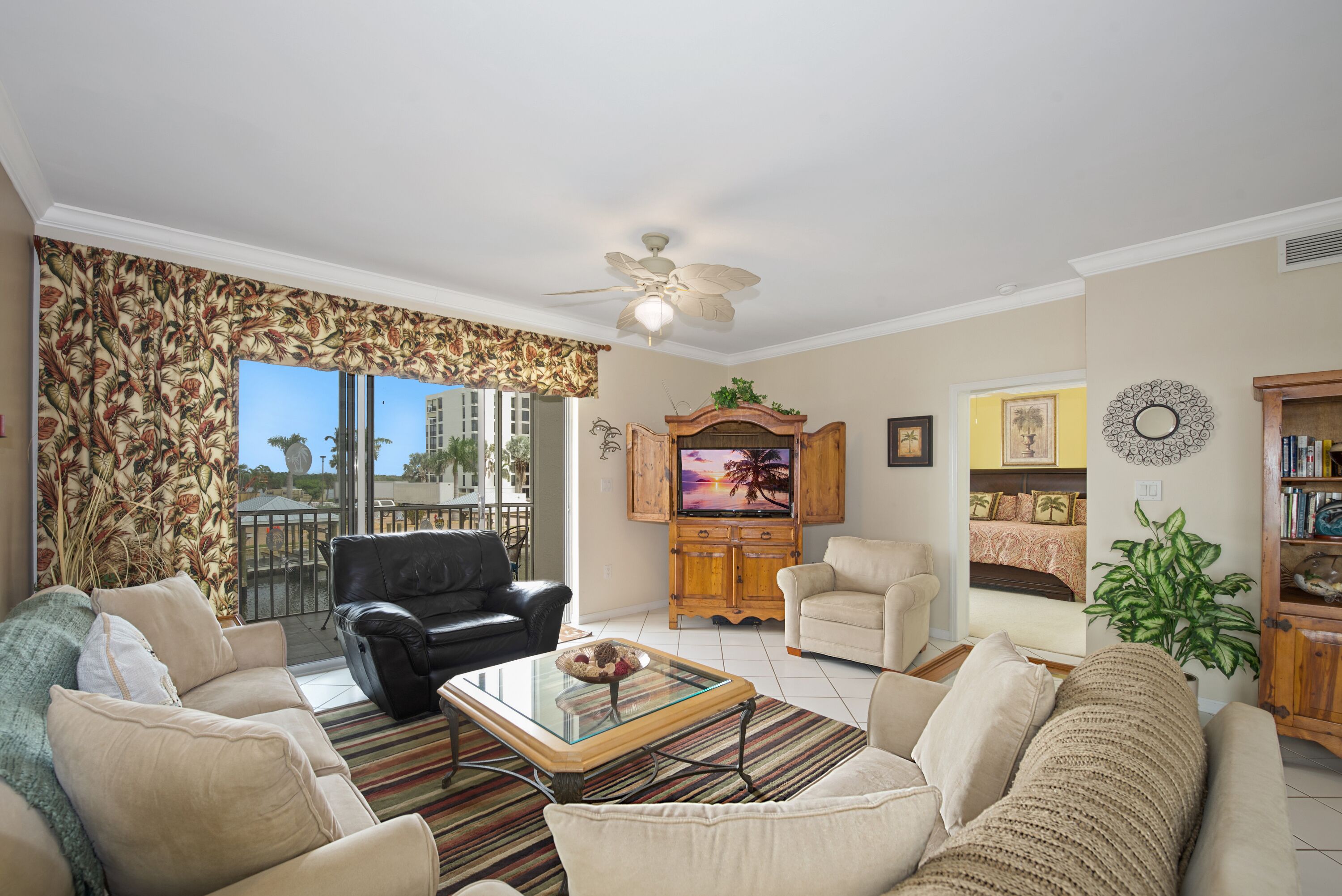 A living room with a sofa, armchairs, a coffee table, a TV, and a ceiling fan.