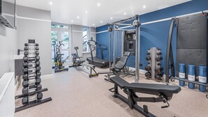Un gimnasio moderno con diversos equipos de ejercicio, incluyendo mancuernas, cintas de correr y máquinas de pesas.