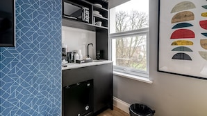 Una cocina moderna con lavavajillas incorporado, cafetera y ventana con vistas a árboles.