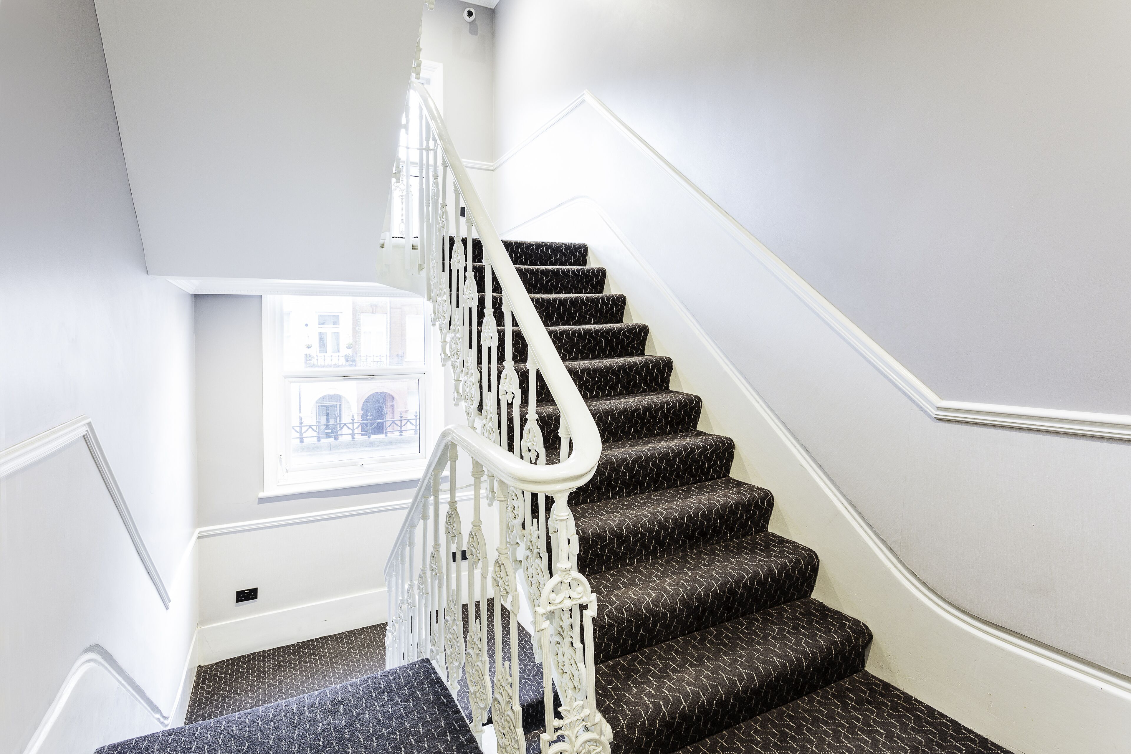 A staircase with white railings and patterned carpet.