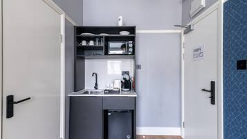 A compact kitchenette with a microwave, coffee maker, and small refrigerator.