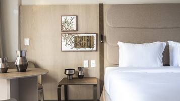 Una habitación de hotel con una cama, una mesita de noche con dos jarrones y dos obras de arte enmarcadas en la pared.