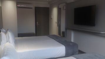 Quarto de hotel com duas camas, uma TV de tela plana na parede e um aparelho de ar condicionado.