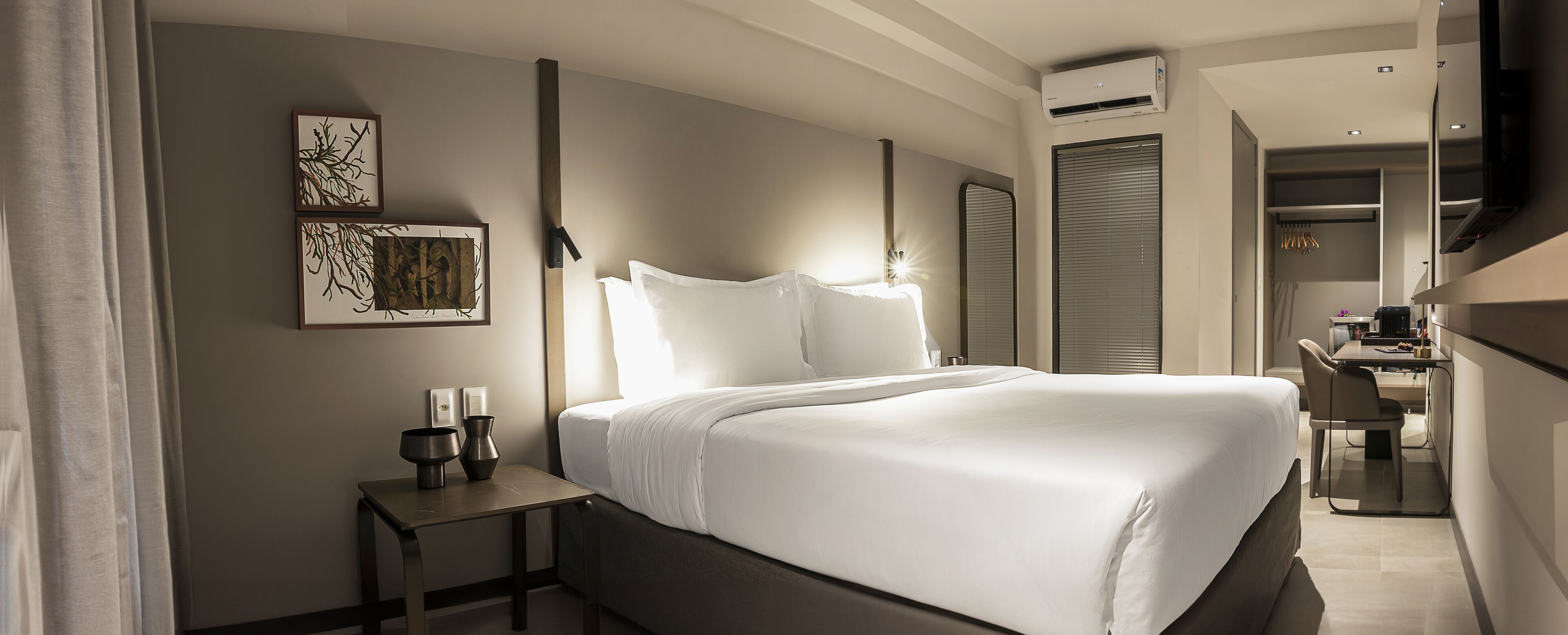 Ein modernes Hotelzimmer mit einem großen Bett, einem Nachttisch und einem Schreibtisch mit Stuhl.