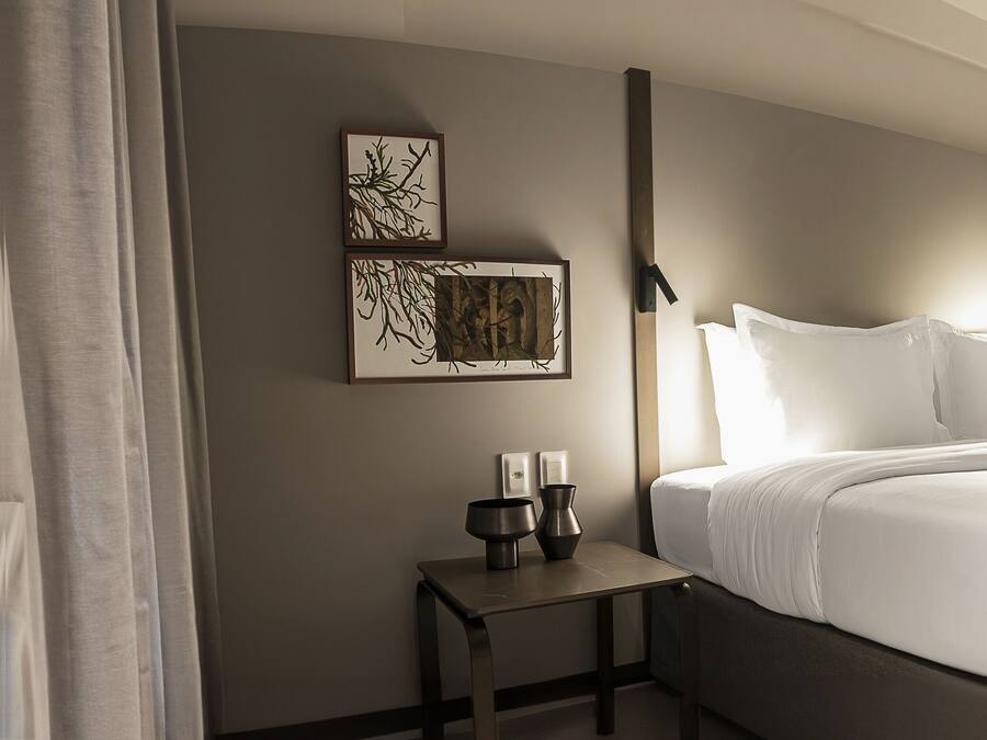 Ein modernes Hotelzimmer mit einem großen Bett, einem Nachttisch und einem Schreibtisch mit Stuhl.