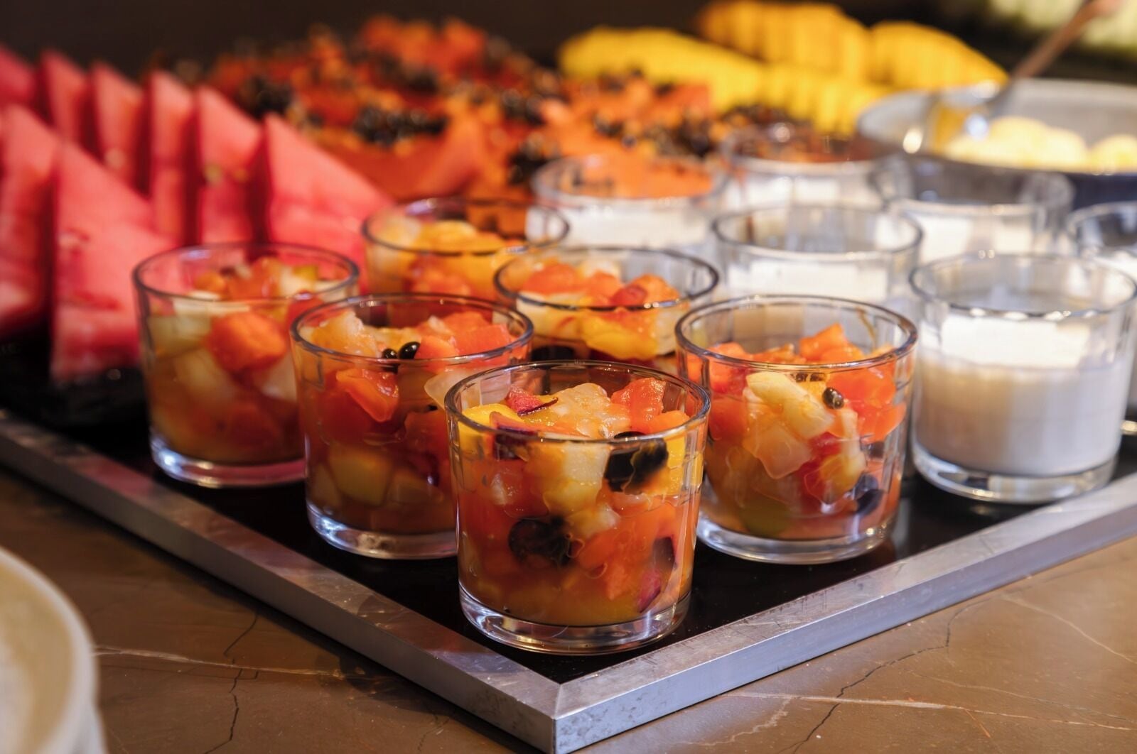 Uma bandeja com copos de fruta e uma vela.