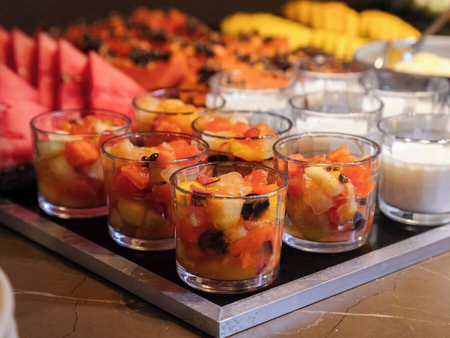 Uma bandeja com copos de fruta e uma vela.