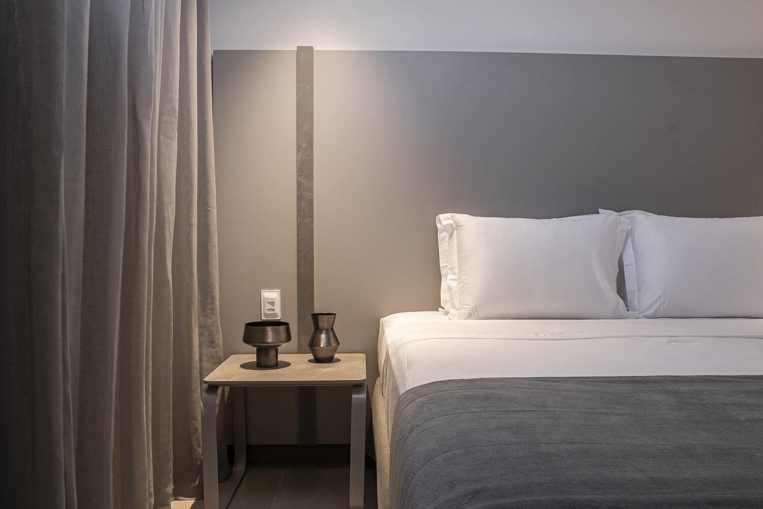 Een hotelkamer met een bed, een nachtkastje met een lamp en een stopcontact.