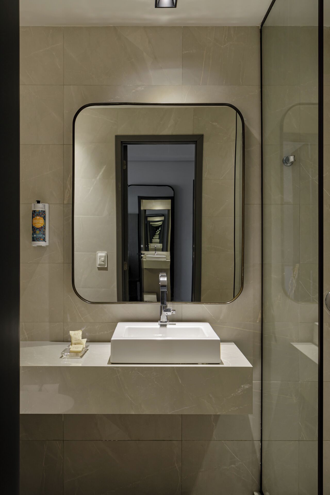 A modern bathroom with a large mirror, a white sink, and a shower area.
