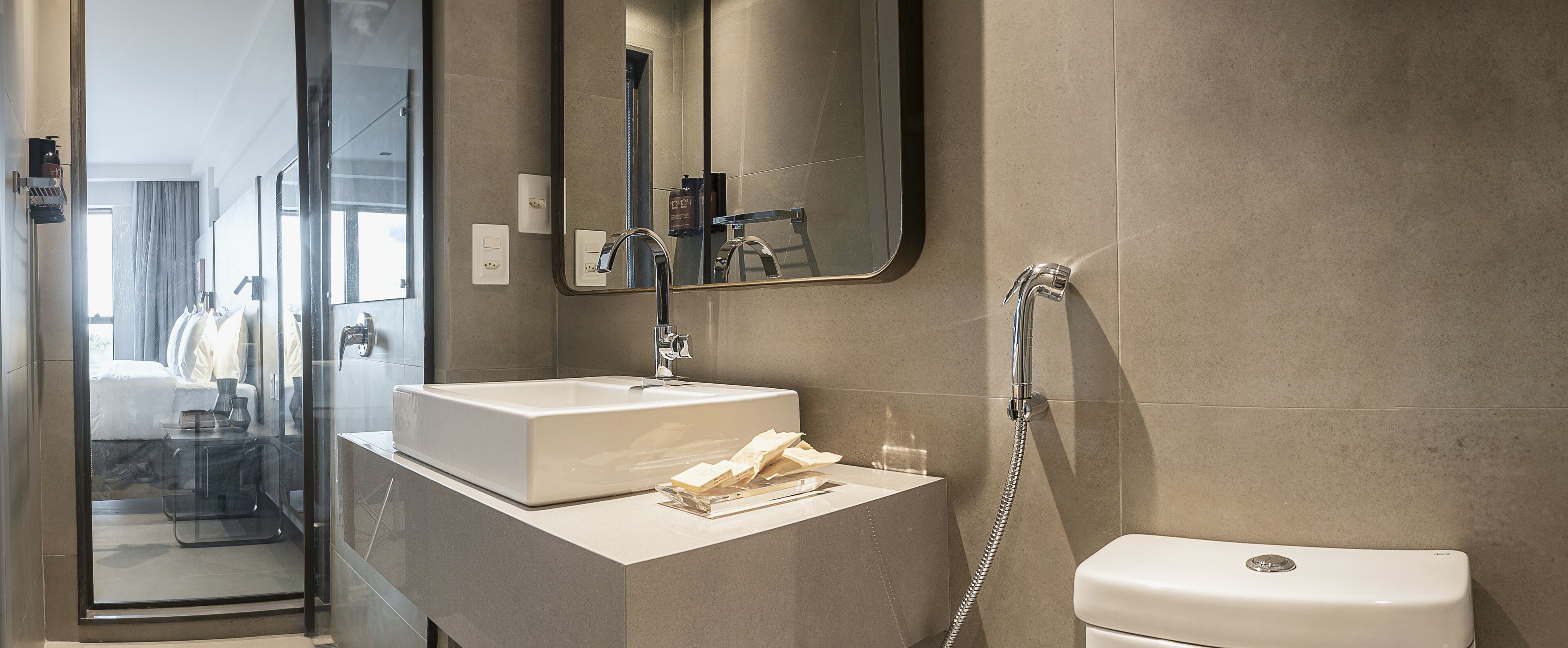 Un baño moderno con un lavamanos blanco, un espejo y una ducha.