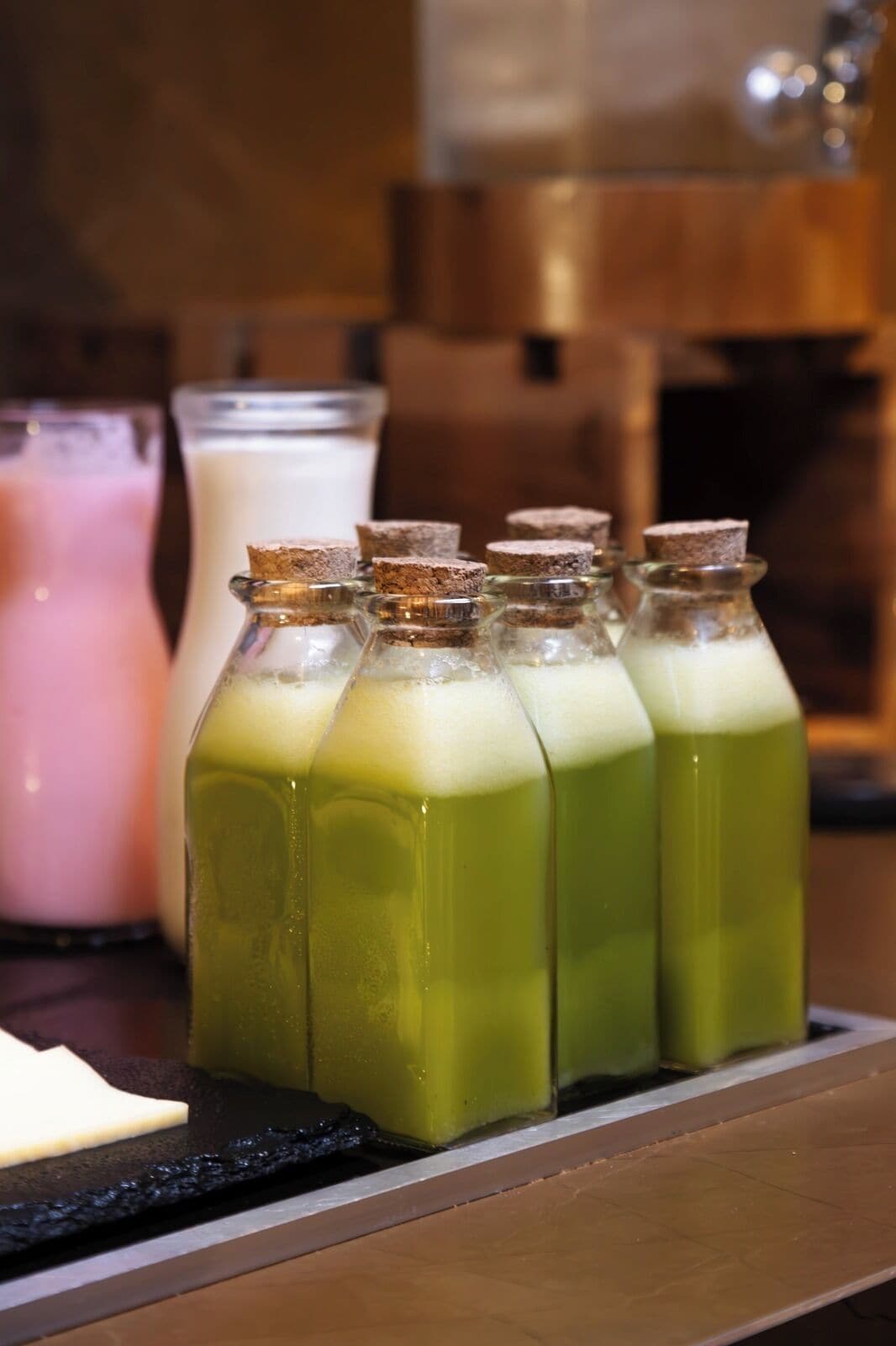 Botellas verdes en fila con tapones de corcho sobre una encimera.