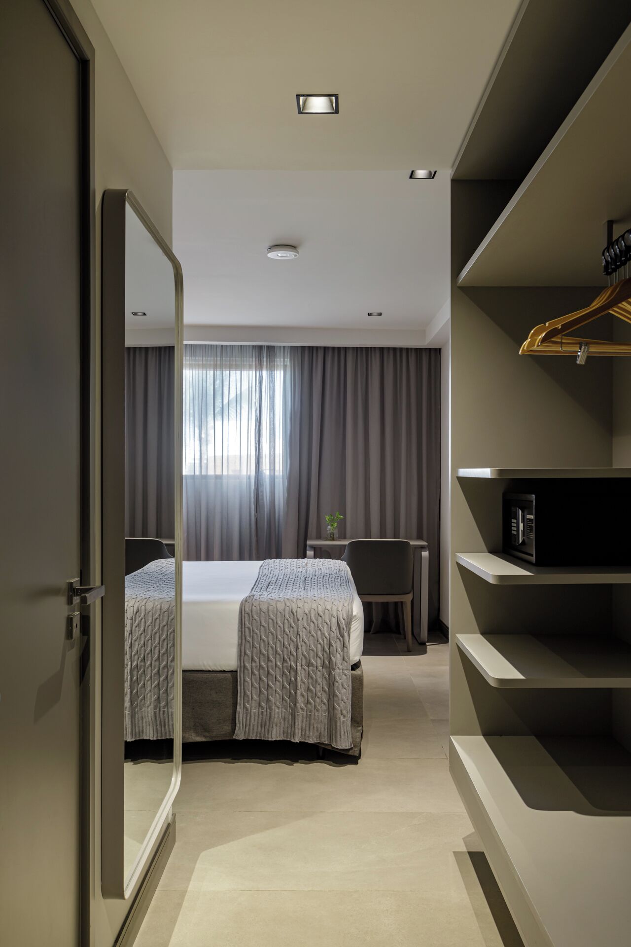 Een moderne hotelkamer met een groot bed, een bureau, een stoel en een kledingkast.