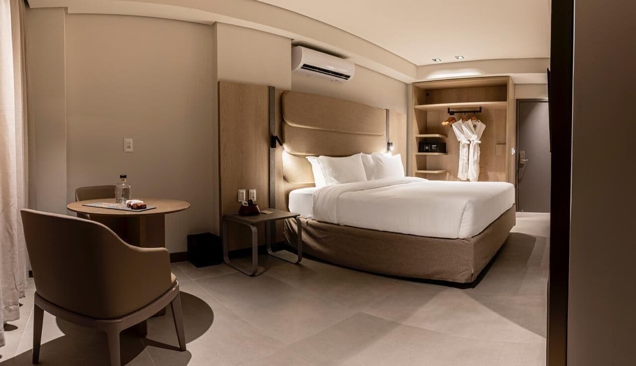 Una habitación de hotel moderna con una cama grande, un escritorio pequeño, una silla y un armario.