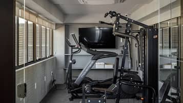 Ein Fitnessraum mit Trainingsgeräten, einem Fernseher und einem Schild mit der Aufschrift 'PHYSALIS ACADEMIA'.