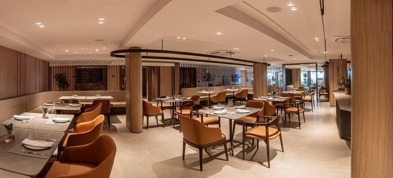 Um restaurante moderno com várias mesas e cadeiras, apresentando um design limpo e contemporâneo.