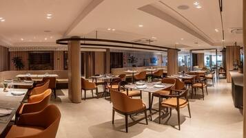 Um restaurante moderno com várias mesas e cadeiras, apresentando um design limpo e contemporâneo.