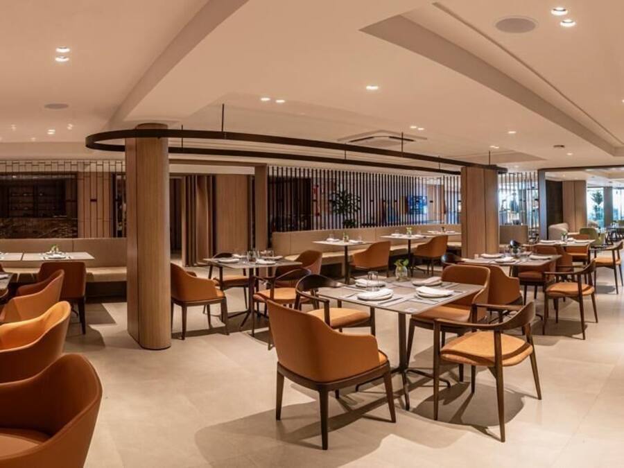 Un restaurant moderne doté de nombreuses tables et chaises, et présentant un design épuré et contemporain.