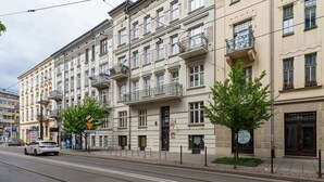 A multi-story building with balconies, a street in front, and a car parked on the side. - Cozy Studio in the Center | 1.3 km from the Main Square (Kraków)