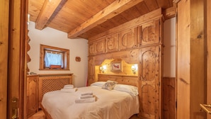 A wooden room with a bed, wooden cabinets, and a window with curtains. - Casa Lacedel 1 on Ski slopes (Cortina d´Ampezzo)