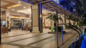 Un'hall d'albergo con zona piscina, posti a sedere all'aperto e una scala che conduce ai piani superiori.