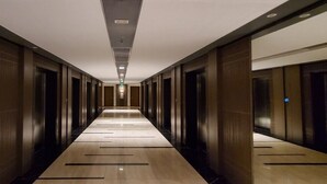 Un long couloir étroit, bordé de part et d’autre d’une série de portes donnant sur des pièces individuelles.