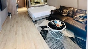 Une chambre d’hôtel moderne, équipée d’un lit, d’un canapé en cuir, d’une table basse et d’un grand miroir.