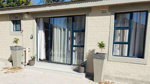 A building with a brick facade, large sliding glass doors, and potted plants. - Contemporary 2 bed in Suburbs - 2080 (Bulawayo)
