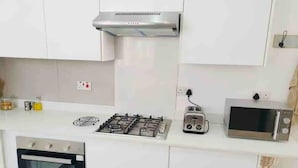 A kitchen with white cabinets, a gas stove, a toaster, a microwave, and an oven. - Contemporary 2 bed in Suburbs - 2080 (Bulawayo)