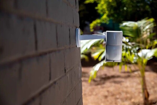 A security camera mounted on a brick wall. - Chic Modern House on Neasden - 2085 (Bulawayo)