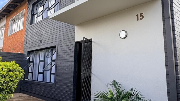 A two-story residential building with a flat roof, a balcony on the upper floor, and a garage entrance. - Chic Modern House on Neasden - 2085 (Bulawayo)
